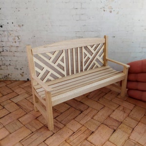 Op de afbeelding: Een houten bank met een geometrisch patroon op de rugleuning. De bank is gemaakt van licht hout en heeft een natuurlijke afwerking.