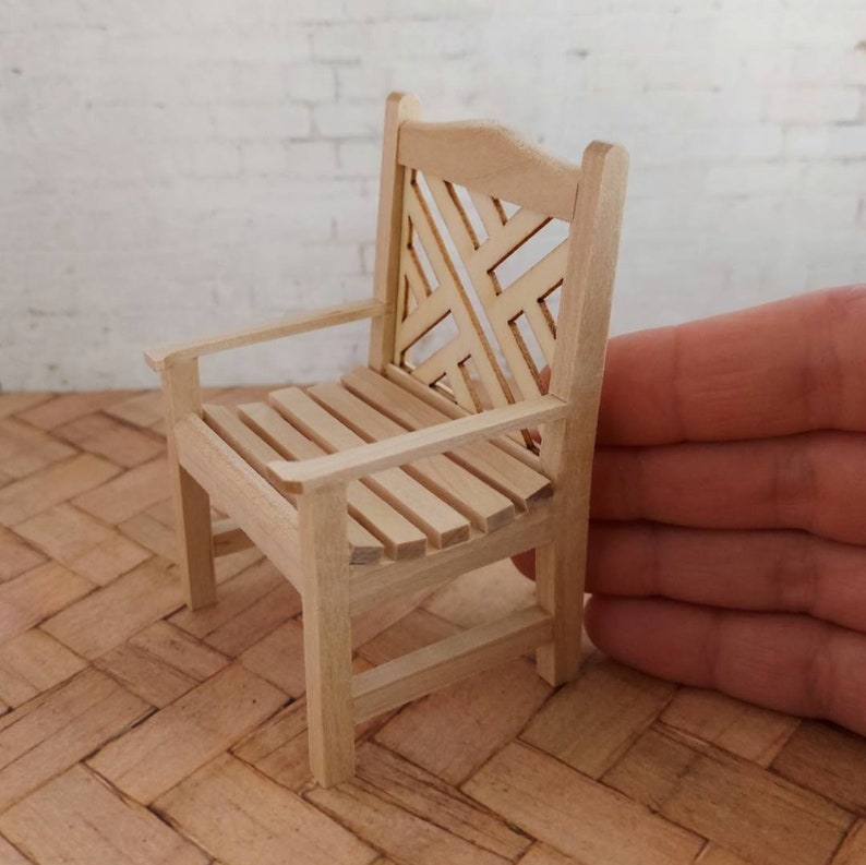 Op de afbeelding: Een houten stoel met een latten zitting en een geometrisch patroon op de rugleuning. De stoel is gemaakt van natuurlijk hout en heeft een rustieke uitstraling.