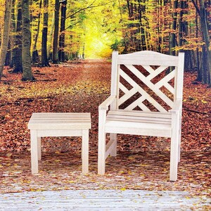 Op de afbeelding: Een houten stoel met een latten rugleuning en een bijpassende houten bijzettafel. De stoel en tafel staan in een bossetting met herfstbladeren.