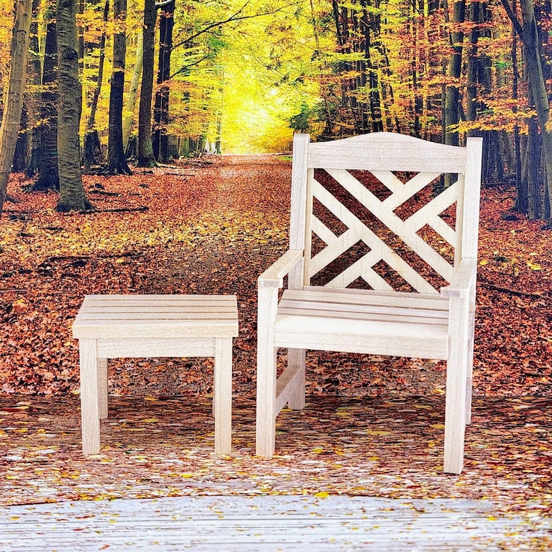 Op de afbeelding: Een houten stoel met een latten rugleuning en een bijpassende houten bijzettafel. De stoel en tafel staan in een bossetting met herfstbladeren.
