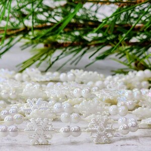 May include: White snowflake garland with iridescent white beads. The garland is made of plastic and is perfect for decorating a Christmas tree or other holiday decor.