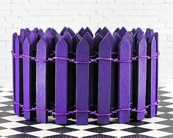 May include: A purple picket fence made of wooden slats, connected by wire, stands on a black and white checkered floor.