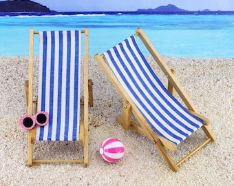 May include: Two wooden striped beach chairs with a pink beach ball in the center. The chairs are on a sandy beach with a blue sky and ocean in the background.