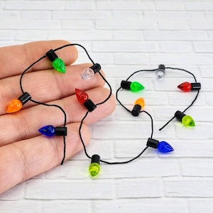 May include: A string of miniature Christmas lights with bulbs in various colors, including red, green, blue, orange, and yellow. The lights are strung on black thread and are perfect for decorating a miniature Christmas tree or other holiday crafts.