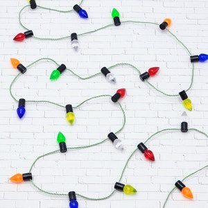 May include: A string of miniature Christmas lights with a variety of colors, including red, green, blue, yellow, and clear. The lights are strung on a white background.