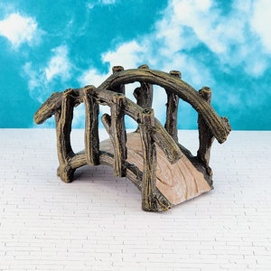 May include: A miniature wooden bridge with a rustic brown finish. The bridge has a curved design and is made of multiple pieces of wood that are connected together. The bridge is perfect for adding a touch of nature to a miniature garden or fairy garden.