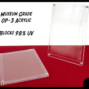 May include: Two clear acrylic display cases with silver screws. The cases are museum grade and block 98% UV. The text "Museum Grade OP-3 Acrylic Blocks 98% UV" is printed on a white background.