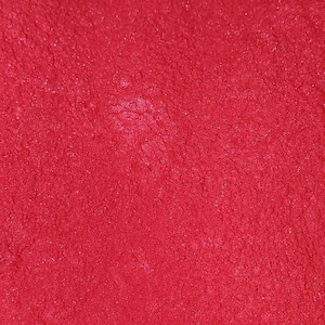 May include: Close-up of a textured, bright red surface. The surface has a slightly uneven texture with small, sparkling highlights, creating a vibrant and eye-catching appearance. The overall effect is a rich, solid color.