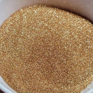 May include: A bowl filled with fine gold glitter. The glitter is very fine and has a shimmery finish.