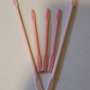 May include: Five pink silicone spatulas of varying sizes. The spatulas have rounded edges and a pointed tip.
