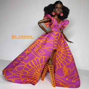May include: A black doll wearing a purple and orange dress with a high slit and a long train. The dress has a geometric pattern. The doll is wearing orange high-heeled sandals.