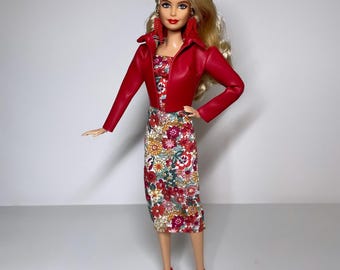 May include: A blonde doll wearing a red leather jacket, a floral print dress, and red heels.