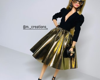 May include: A fashion doll wearing a black top with a plunging neckline and a gold metallic skirt. The doll has long blonde hair and is wearing black sunglasses and earrings.
