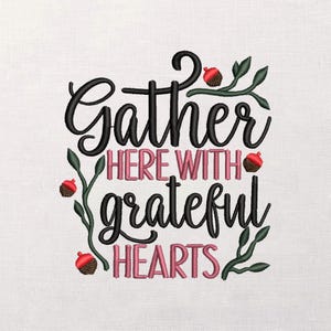 Könnte beinhalten: Gesticktes Kunstwerk mit den Worten "Gather Here With Grateful Hearts" in schwarzer und rosa Schrift. Das Design umfasst grüne Blätter und rote und braune Eicheln auf weißem Hintergrund.