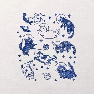 May include: Embroidered design featuring several cats in space suits, floating among stars, planets, and a spaceship. The cats are depicted in various poses, with a mix of solid and outline styles, all in shades of blue on a white background.