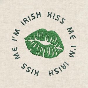 May include: Embroidered design featuring a green kiss and the text "I'm Irish Kiss Me" in a circular pattern. The design is on a beige fabric, suitable for St. Patrick's Day.