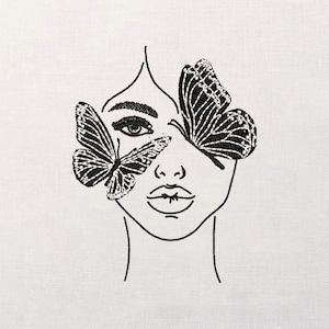 May include: Embroidered artwork featuring a woman's face with two butterflies obscuring her eyes. The butterflies are black with detailed wing patterns. The design is on a white fabric, with the face and butterflies outlined in black thread.