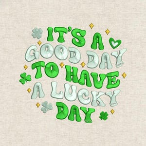 May include: Embroidered design with the text "IT'S A GOOD DAY TO HAVE A LUCKY DAY" in green and white bubble letters. The design includes shamrocks and gold stars on a beige background.