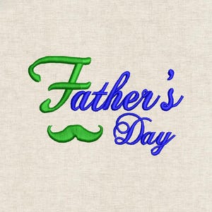 以下が含まれることがあります： ベージュの背景に、緑と青で刺繍された父の日デザイン。「Father's」の文字は緑色の筆記体で、下に緑色の口ひげがあります。「Day」は青色の筆記体です。