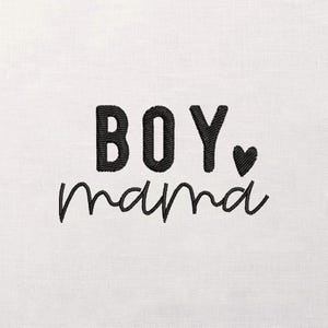May include: White fabric with black embroidered text that reads "BOY, mama" with a small heart. The word "BOY" is in a bold, blocky font, while "mama" is in a cursive script.