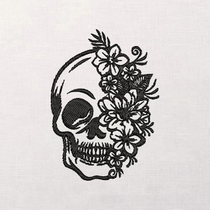 May include: Black embroidered skull design with floral accents. The skull is depicted in profile, with detailed stitching outlining the features and the flowers. The flowers are clustered on the right side of the skull.