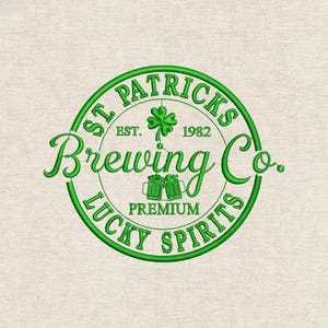 Puede incluir: Logotipo bordado en verde para St. Patrick's Brewing Co. con un trébol, dos jarras de cerveza y las palabras "Lucky Spirits" y "Premium". El logotipo es circular con el texto "St. Patricks" en la parte superior y "Brewing Co." en cursiva.