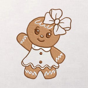 May include: Embroidered gingerbread cookie design. The gingerbread person is brown with white icing details, wearing a white dress with brown buttons and a white bow. The design is on a white background.