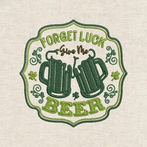 May include: Embroidered design featuring two green beer mugs with the text "FORGET LUCK Give Me BEER" in green and brown. The design includes shamrocks and decorative flourishes, all set within a green-bordered frame.