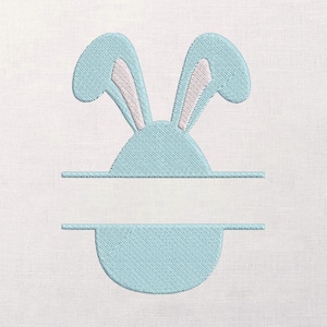 May include: A light blue embroidered design featuring bunny ears with pink inner ears, a rounded head, and a horizontal line. Below the line is a semi-circular shape, all on a white background.