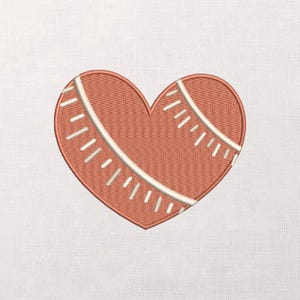 Könnte beinhalten: Gesticktes Herzdesign im Baseball-Stil. Das Herz hat eine gedämpfte orange-rote Farbe mit weißen Nahtdetails. Das Design befindet sich auf einem weißen Stoffhintergrund.