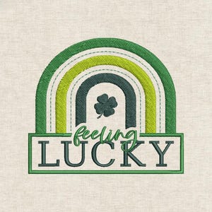 Può includere: Design ricamato con un arcobaleno verde e giallo e un quadrifoglio. Il testo "feeling LUCKY" è visualizzato sotto l'arcobaleno in verde. Il design è su uno sfondo di tessuto beige, perfetto per San Patrizio.