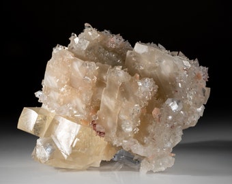 May include: A cluster of translucent, pale yellow and white crystals with a few pink accents. The crystals are arranged in a layered formation, creating a unique and intricate display.