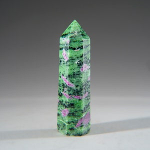 May include: A green and pink gemstone point, also known as a crystal, with a pointed tip and a faceted shape.