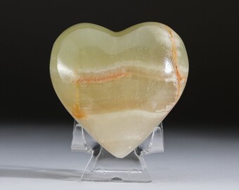 May include: A heart-shaped green onyx stone with white and orange stripes, displayed on a clear plastic stand.