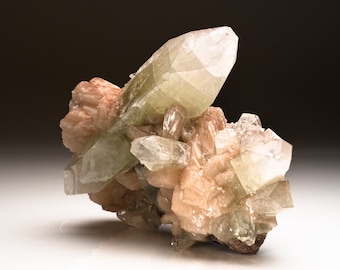 May include: A cluster of green and pink crystals with a glassy, translucent appearance. The crystals are arranged in a natural, organic formation, showcasing their unique shapes and textures.