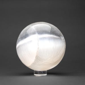 Op de afbeelding: Een witte selenietbol met een doorschijnende, bewolkte uitstraling. De bol staat op een heldere standaard.