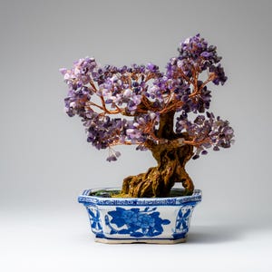 Puede incluir: Un bonsái decorativo con tronco marrón y ramas de alambre de cobre, adornado con piedras de amatista moradas. El árbol está plantado en una maceta de cerámica blanca y azul con un diseño floral. Un artículo de decoración único.