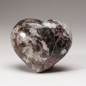 May include: A heart-shaped polished stone with a black, white, and pink marbled pattern.