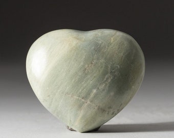 May include: A heart-shaped stone sculpture carved from green and white marble. The sculpture has a smooth, polished surface and is a light green color.