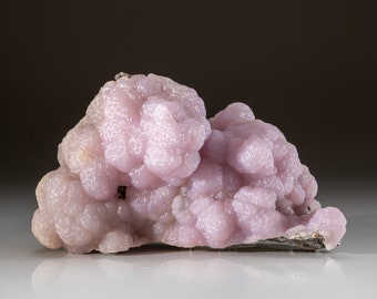 May include: A large, pink, botryoidal, mineral specimen with a smooth, textured surface.