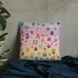 May include: Square throw pillow featuring a colorful pattern of whimsical cartoon creatures. The design includes a variety of shapes and colors, set against a pastel striped background. The pillow is resting on a dark blue surface.