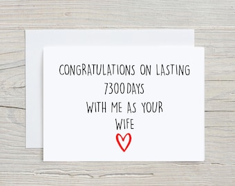 Puede incluir: Tarjeta blanca con texto negro que dice "Felicidades por durar 7300 días conmigo como tu esposa" con un corazón rojo.