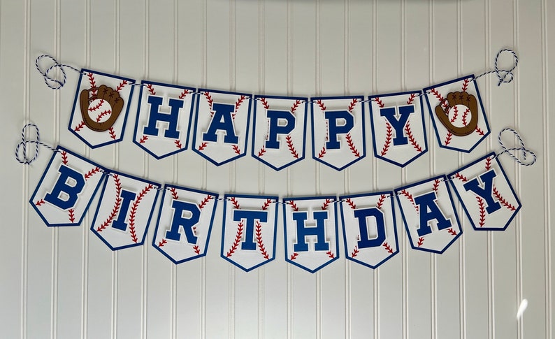 Pode incluir: Uma faixa de beisebol branca e azul com as palavras "Happy Birthday" em letras azuis. A faixa tem um padr&atilde;o de pontos de beisebol vermelho e branco e recortes de luvas de beisebol marrons.