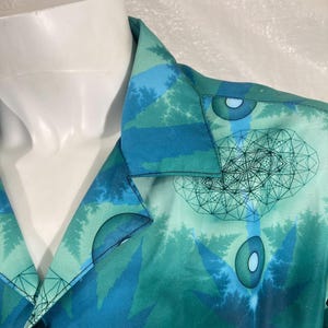 Op de afbeelding: Een blauw en groen geprint overhemd met een geometrisch ontwerp. Het overhemd heeft een knoopsluiting en een enkele knoop.