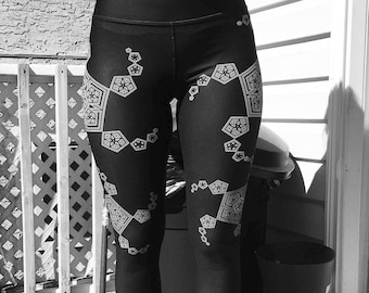 May include: Black leggings with a white geometric pattern. The pattern is made up of repeating hexagonal shapes.