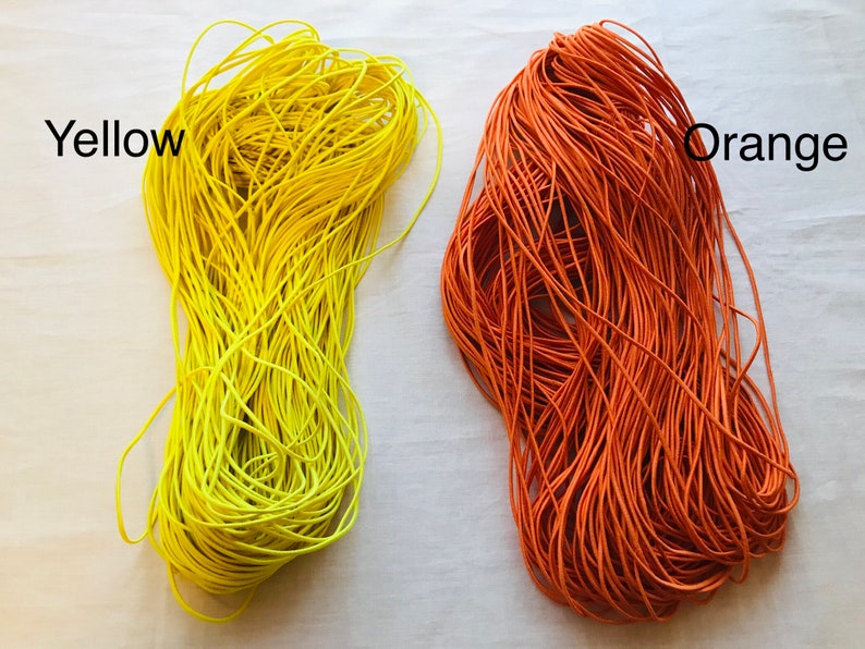 May include: Two spools of elastic cord, one yellow and one orange. The spools are labeled "Yellow" and "Orange".