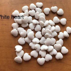 May include: A pile of white heart-shaped beads. White heart.