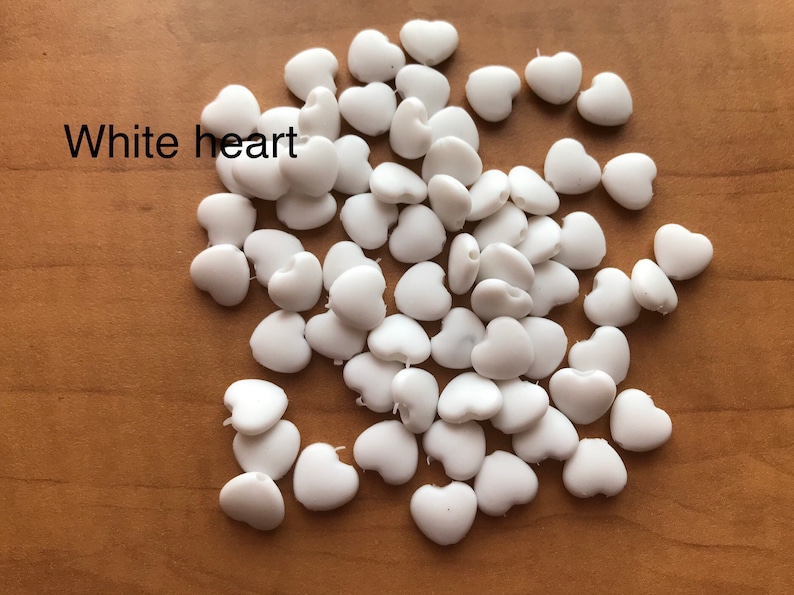 May include: A pile of white heart-shaped beads. White heart.