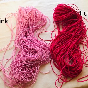 May include: Two spools of elastic cord, one pink and one fuchsia. The spools are labeled "Pink" and "Fushia".