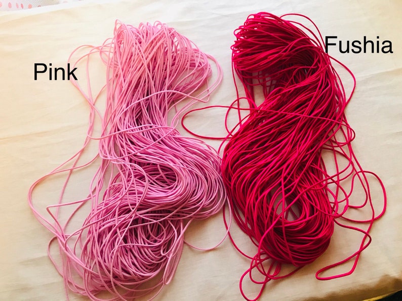 May include: Two spools of elastic cord, one pink and one fuchsia. The spools are labeled "Pink" and "Fushia".